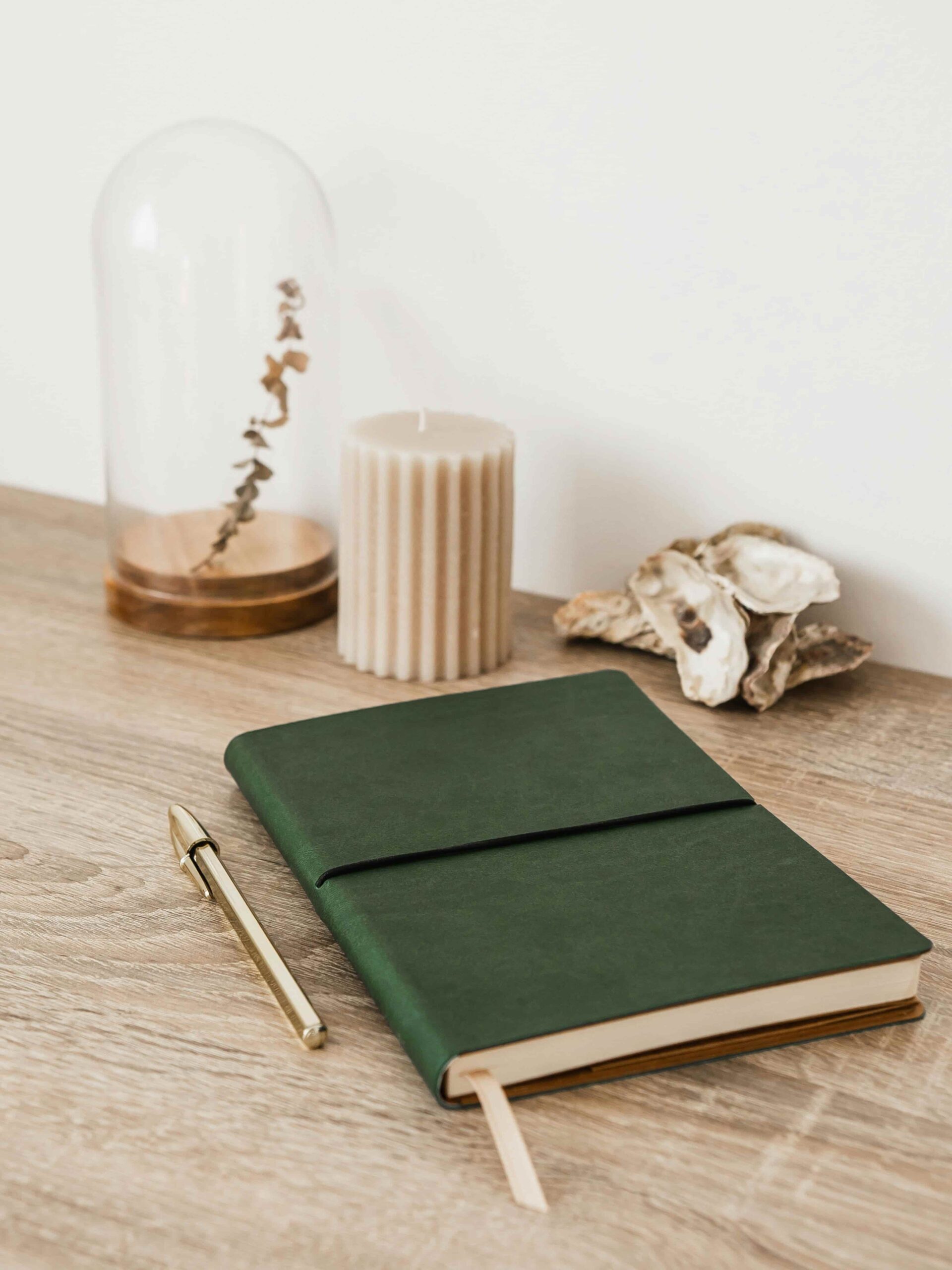 A green leather journal rests on a wooden table near a softly glowing candle, evoking quiet nighttime reflection after sleep anxiety therapy.